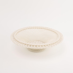 May include: A round, off-white woven basket with a wide, flared rim and a shallow, concave center. The structure features a detailed, repetitive lattice pattern throughout the body, supported by a small, circular base at the bottom.