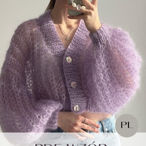 May include: A light purple, open-weave cardigan with large, iridescent buttons. The long-sleeved sweater has a V-neck and a cropped fit. The image also includes the text "PDF WZÓR LACE kardigan".