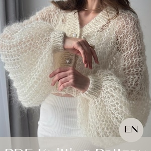 Könnte beinhalten: Cremefarbene Spitzenstrickjacke mit V-Ausschnitt und Ballonärmeln. Die Strickjacke hat herzförmige Knöpfe und ist aus einem zarten, offen gewebten Strick gefertigt. Der Text "PDF Knitting Pattern LACE cardigan" steht unten.