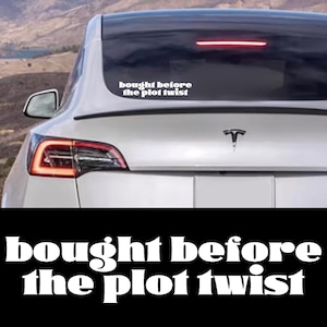 May include: A white Tesla Model 3 with a rear window sticker that reads "bought before the plot twist".
