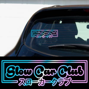 May include: A blue and pink gradient sticker with the text "Slow Car Club" and the Japanese translation "スローカークラブ" in a white rectangle.