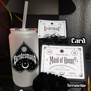May include: A frosted glass cup with a straw, a black scrunchie, and two cards. The cup has a gothic design with the word "Bridesmaid" and a crescent moon. The cards read "Bridesmaid?" and "Maid of Honor?" with Ouija board elements.