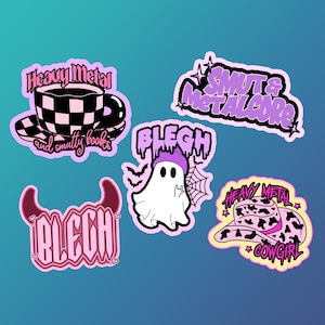 May include: Five pink and purple stickers with various designs. One sticker features a ghost with a purple hat and the text "BLEGH". Another sticker features a teacup with a black and white checkered pattern and the text "Heavy Metal and smutty books". A third sticker features a cowboy hat with a leopard print and the text "Heavy Metal Cowgirl". A fourth sticker features the text "BLEGH" in a gothic font. The final sticker features the text "SMUT & METALCORE".