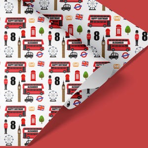 May include: White wrapping paper with a repeating pattern of red double-decker buses, red telephone booths, Big Ben, the London Eye, crowns, and the Union Jack flag. The text "Happy Birthday" and the number "8" are repeated throughout the pattern. The text "Alexander" is also repeated throughout the pattern.