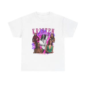 May include: White t-shirt with a pink and purple graphic print of a group of women. The graphic includes the text "KRISTEN Doute".