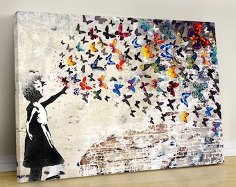 May include: Canvas art print featuring a black and white silhouette of a girl releasing colorful butterflies. The butterflies are in shades of red, yellow, blue, and green, set against a distressed, textured background with brick details.