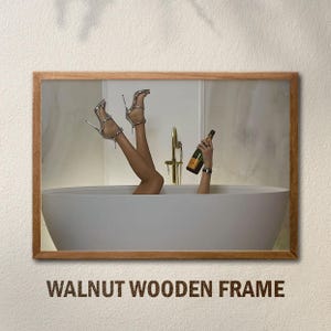 Op de afbeelding: Een ingelijste afbeelding van een persoon in een bad, met de benen omhoog, met zilveren hoge hakken. Een hand houdt een champagnefles vast. De lijst is van walnotenhout, met de tekst "WALNUT WOODEN FRAME" onderaan.