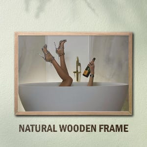 Op de afbeelding: Een ingelijste afbeelding met een persoon in een badkuip met omhooggestoken benen, zilveren hoge hakken en een champagnefles. De afbeelding is ingelijst met een natuurlijke houten lijst. De tekst "NATURAL WOODEN FRAME" staat onderaan.
