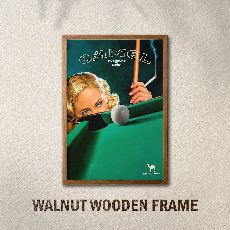 K&ouml;nnte beinhalten: Vintage Camel-Zigarettenwerbung in einem Walnussholzrahmen. Das Kunstwerk zeigt eine Frau mit blauen Augen, die &uuml;ber einen gr&uuml;nen Billardtisch blickt. Eine brennende Zigarette und ein Billardqueue sind ebenfalls zu sehen. Das Camel-Logo und der Text befinden sich oben.