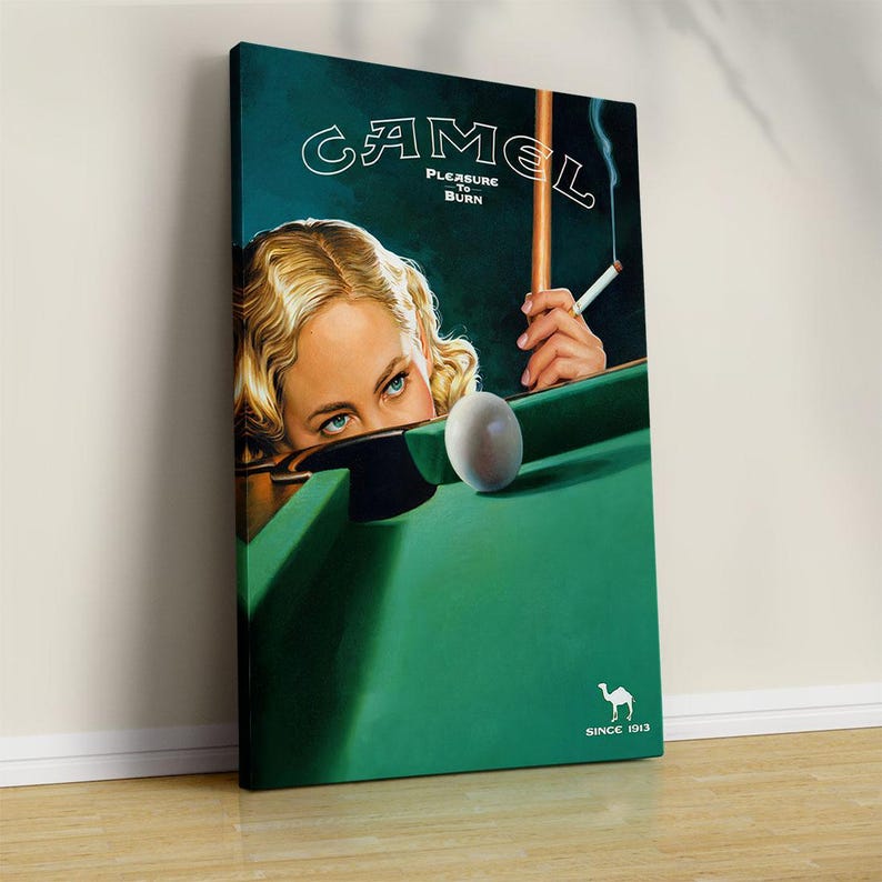 K&ouml;nnte beinhalten: Vintage-Leinwanddruck mit einer Frau mit blauen Augen und blonden Haaren, die Billard spielt. Der Druck zeigt das Camel-Logo und den Text "Pleasure to Burn" und "Since 1913". Der Billardtisch ist gr&uuml;n, mit einer wei&szlig;en Kugel.