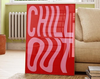 Op de afbeelding: Een rode en roze poster met de tekst "CHILL OUT" in een gestileerd lettertype. De poster hangt aan een muur in een woonkamer met een bank en een plant.