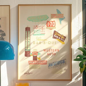 Può includere: Una stampa incorniciata con insegne in stile vintage per ristoranti e attività commerciali, tra cui "Winstead's" e "Joe's Bar-B-Que." Le insegne sono in vari colori e caratteri, con un'estetica retrò. La stampa è esposta su una parete.
