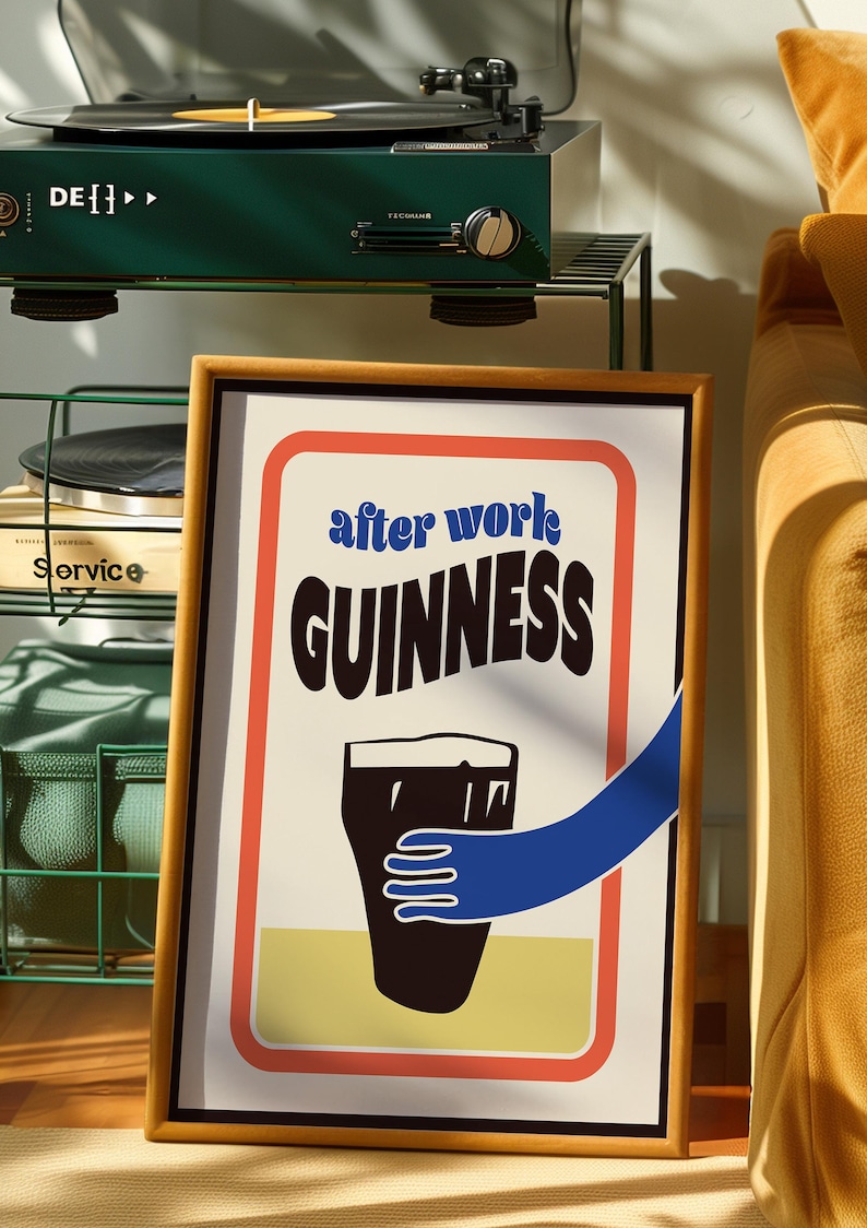 Op de afbeelding: Een ingelijste poster met een witte achtergrond en rode, oranje en gele randen. De poster toont een zwart-witte illustratie van een pint Guinness met een blauwe hand die ernaar reikt. De tekst "after work GUINNESS" is in zwart-wit gedrukt.