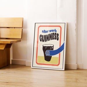 Op de afbeelding: Een wit ingelijste poster met een rood, wit en blauw ontwerp. De poster toont een glas Guinness-bier met een hand die ernaar reikt. De tekst op de poster luidt "after work GUINNESS".