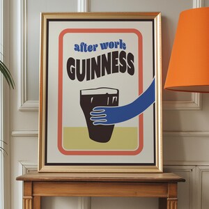 Op de afbeelding: Een ingelijste poster met een vintage ontwerp met een glas Guinness-bier met de tekst "after work GUINNESS" in blauw en rood.