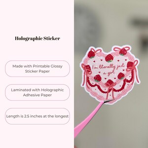 Puede incluir: Una pegatina hologr&aacute;fica rosa y roja con un dise&ntilde;o de pastel en forma de coraz&oacute;n. El pastel est&aacute; decorado con fresas, lazos y el texto "I'm literally just a girl". La pegatina mide 2,5 pulgadas de largo.