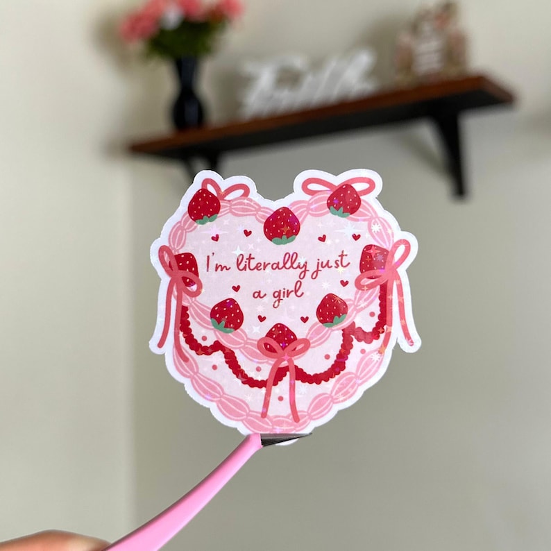 Puede incluir: Pegatina rosa en forma de coraz&oacute;n con un dise&ntilde;o de pastel rosa y blanco. El pastel est&aacute; decorado con fresas y el texto "Soy literalmente solo una chica".