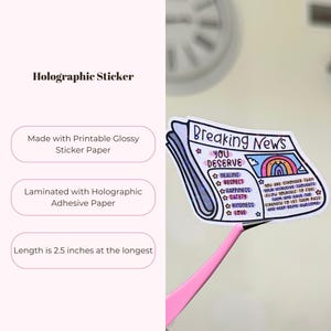 May include: A holographic sticker with a newspaper design that says "Breaking News You Deserve" with a rainbow and a list of positive affirmations including healing, respect, happiness, safety, kindness, and love. The sticker is 2.5 inches long.