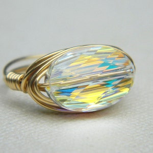 May include: A gold wire wrapped ring with a clear iridescent oval crystal bead.