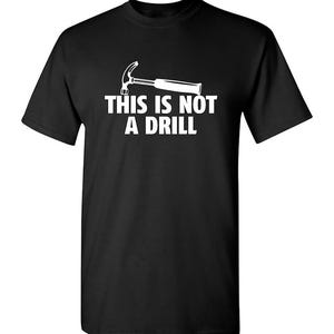 May include: Black t-shirt with a white graphic of a hammer and the text "THIS IS NOT A DRILL". The short-sleeved shirt is made of a soft material and is suitable for casual wear.