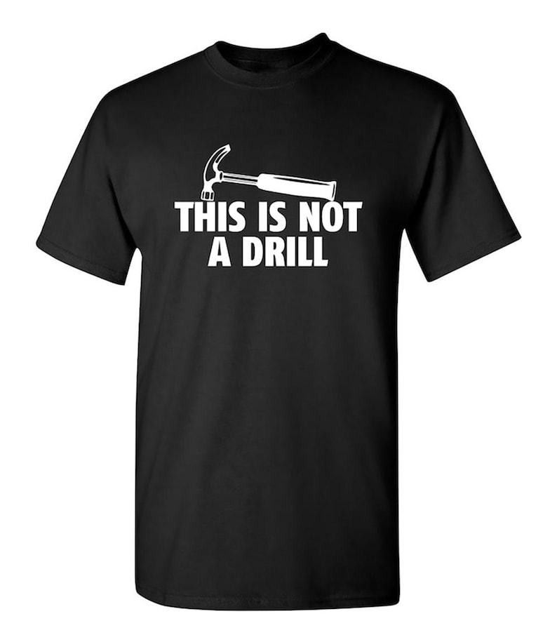 May include: Black t-shirt with a white graphic of a hammer and the text "THIS IS NOT A DRILL". The short-sleeved shirt is made of a soft material and is suitable for casual wear.