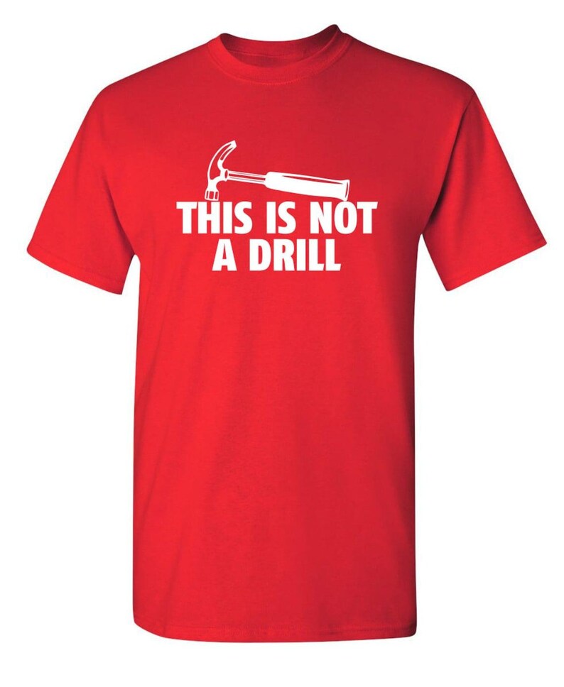 May include: A red t-shirt with a white graphic of a hammer and the text "THIS IS NOT A DRILL". The short-sleeved shirt is made of a soft material and is suitable for casual wear.