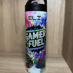 May include: A black and white stainless steel water bottle with a colorful design. The design features a keyboard, a mouse, and the text "Gamer Fuel" in green and purple. The name "Eli" is printed in white on the bottle.