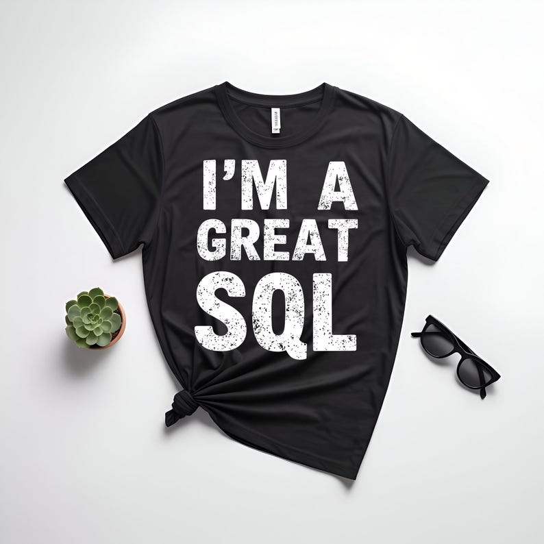 May include: Black t-shirt with the text "I'M A GREAT SQL" in white, distressed font. The shirt is knotted at the bottom. A small potted succulent and black sunglasses are also visible.