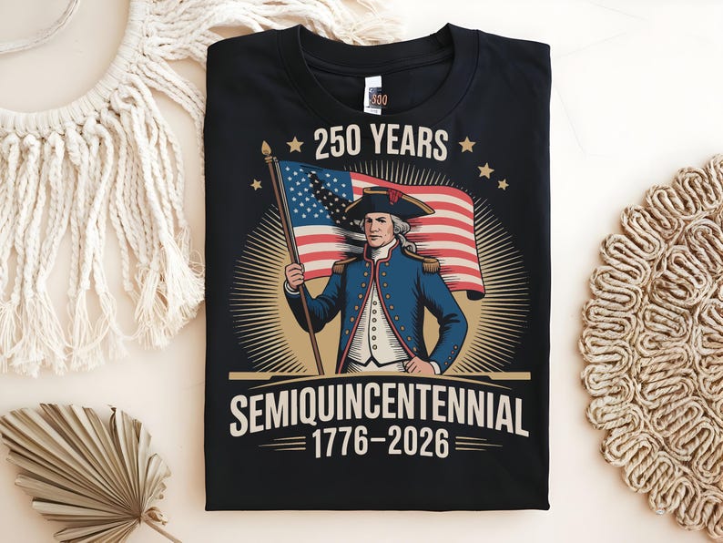 K&ouml;nnte beinhalten: Schwarzes T-Shirt mit einer Grafik zum 250. Jahrestag der Vereinigten Staaten. Das Design zeigt eine Illustration einer historischen Figur, die die amerikanische Flagge h&auml;lt, mit dem Text "250 YEARS SEMIQUINCENTENNIAL 1776-2026".