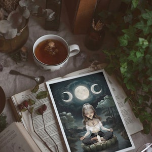 K&ouml;nnte beinhalten: Eine wei&szlig;e Karte mit dunkelblauem Hintergrund, auf der eine Frau auf einer Lotusbl&uuml;te meditiert. Die Frau hat langes, dunkles Haar und tr&auml;gt ein wei&szlig;es Oberteil und eine schwarze Hose. Der Mond befindet sich im Hintergrund mit drei Sichelmonden, die ihn umgeben. Die Karte hat einen wei&szlig;en Rand.