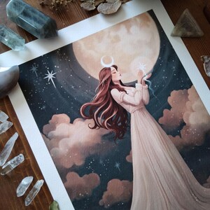 May include: A watercolor painting of a woman with long red hair standing in front of a large, full moon. She is wearing a white dress and holding a small, glowing star in her hand. The background is a dark blue sky with clouds and stars.