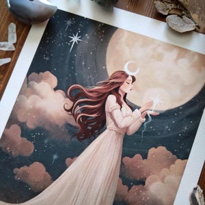 May include: A watercolor painting of a woman with long brown hair wearing a white dress standing in front of a large, full moon. She is holding a small, white star in her hand. The background is a dark blue sky with clouds and stars.