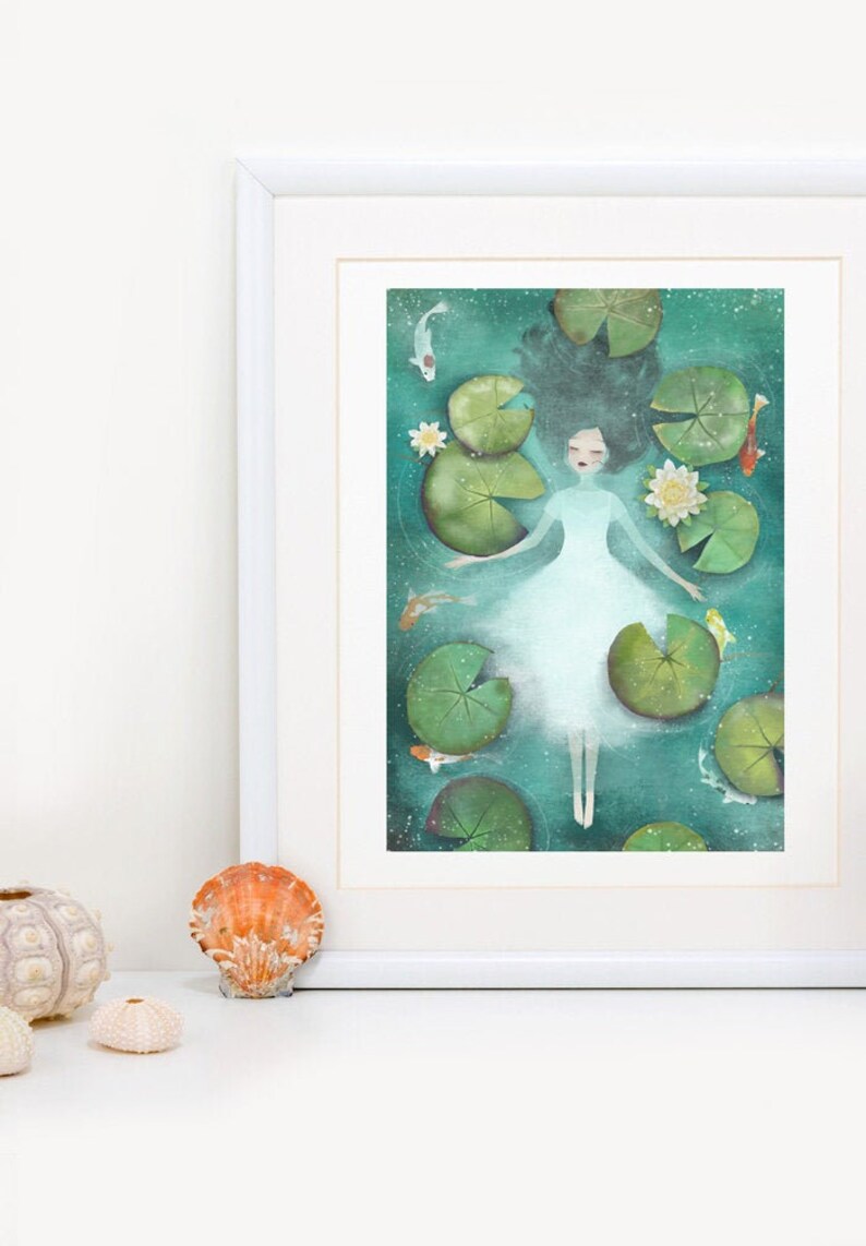 Puede incluir: Una pintura de acuarela de una mujer con un vestido blanco flotando sobre un lecho de nen&uacute;fares en un estanque turquesa. La mujer tiene el pelo largo y oscuro y los ojos cerrados. Hay peque&ntilde;os peces blancos y naranjas nadando a su alrededor.