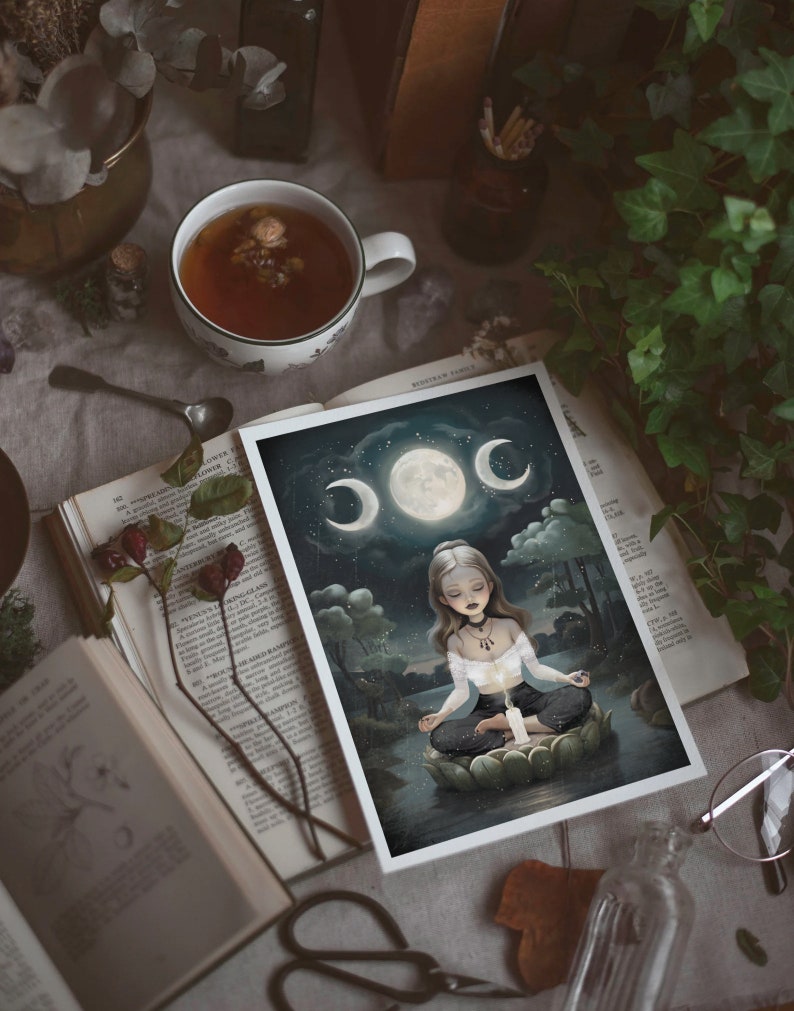 K&ouml;nnte beinhalten: Eine wei&szlig;e Karte mit dunkelblauem Hintergrund, auf der eine Frau auf einer Lotusbl&uuml;te meditiert. Die Frau hat langes, dunkles Haar und tr&auml;gt ein wei&szlig;es Oberteil und eine schwarze Hose. Der Mond befindet sich im Hintergrund mit drei Sichelmonden, die ihn umgeben. Die Karte hat einen wei&szlig;en Rand.