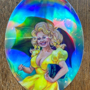 May include: Holographic sticker featuring a smiling woman in a yellow dress holding a rainbow umbrella. The sticker has a vibrant, iridescent finish. The woman is holding a book with the text "DIEGO GOMEZ 2017".
