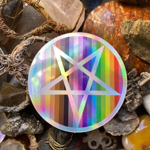 Può includere: Un adesivo rotondo con uno sfondo arcobaleno e un pentagramma bianco al centro. L'adesivo ha una finitura olografica.
