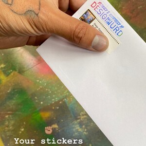 Pode incluir: Um envelope branco com um adesivo na frente. O adesivo tem uma imagem colorida e o texto "DESIGNED & ILLUSTRATED BY DESIGMURD" e "Diego Gomez". O texto "Your stickers will come in an envelope like this" est&aacute; escrito abaixo do envelope.