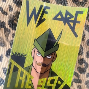 Könnte beinhalten: Ein rechteckiger Aufkleber mit einem holografischen grünen und goldenen Hintergrund. Der Aufkleber zeigt eine Cartoon-Illustration eines Mannes in grünem Hut und Uniform mit den Worten "WE ARE THE ELITE" in Schwarz. Der Aufkleber hat ein glänzendes Finish.