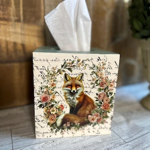 May include: A wooden tissue box cover with a fox and floral design. The box is painted in a light green color and features a white background with a fox surrounded by roses and handwritten script.