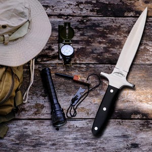 May include: An outdoor adventure kit featuring a survival knife with a black handle, a compass, a flashlight, a fire starter, a tan backpack, and a beige hat. The items are arranged on a weathered wooden surface.