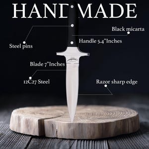 May include: A handmade dagger with a 17.78 cm blade and a 13.72 cm handle. The blade is made of 12C27 steel and has a razor-sharp edge. The handle is black micarta, secured with steel pins. The word "HAND MADE" is at the top.