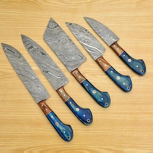 May include: Set of six kitchen knives with blue and brown handles. The blades are made of Damascus steel and have a wavy pattern.