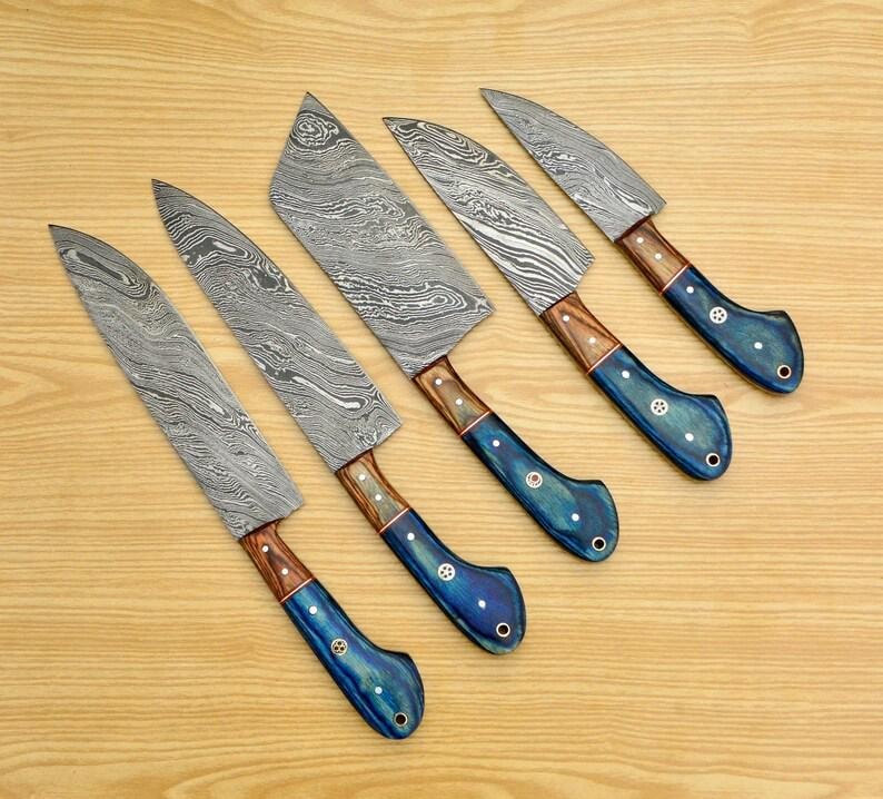 May include: Set of six kitchen knives with blue and brown handles. The blades are made of Damascus steel and have a wavy pattern.