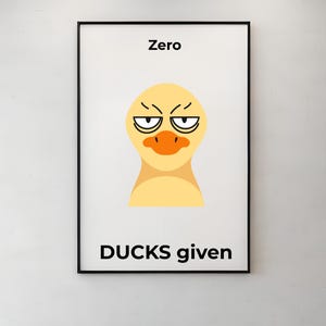 May include: Framed art print featuring a cartoon duck face with an angry expression. The text "Zero" is above the duck, and "DUCKS given" is below. The artwork is in a black frame, mounted on a white wall.
