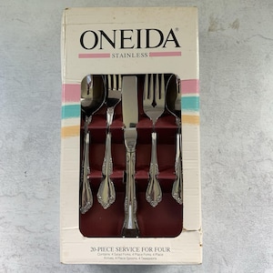 Op de afbeelding: Een 20-delige roestvrijstalen bestekset van Oneida in een rechthoekige doos. De set bevat vier saladevorken, vier dinervorken, vier dinermessen, vier dinerlepels en vier theelepels, allemaal met een decoratief bloemmotief op de handgrepen.