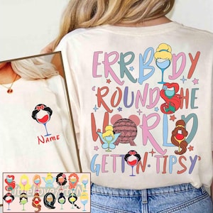 Può includere: T-shirt color crema con la scritta "ERRBODY ROUND THE WORLD GETTIN' TIPSY" in lettere colorate. Il design include immagini di cartoni animati di principesse Disney in calici di vino. Un'immagine più piccola di un design simile è a sinistra.
