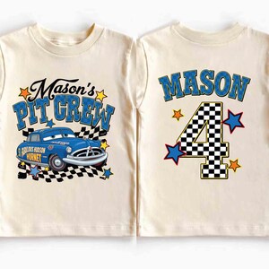 K&ouml;nnte beinhalten: Cremefarbenes T-Shirt mit einem blauen Rennwagen-Motiv und dem Text "Mason's Pit Crew". Auf der R&uuml;ckseite des Shirts steht der Name "Mason" &uuml;ber einer karierten Zahl 4 mit Sternakzenten. Ein lustiges Geburtstags-Shirt.