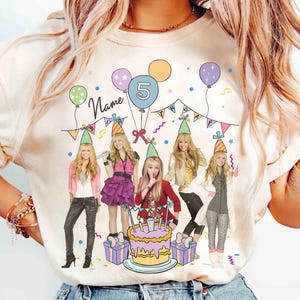 May include: Cream-colored t-shirt featuring a birthday party design. The graphic includes cartoon illustrations of a group of girls, balloons, a cake, and the number 5. The word "Name" is written in cursive.