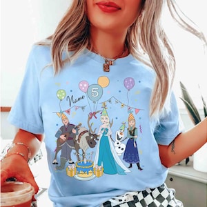 Może przedstawiać: Jasnoniebieska koszulka z motywem urodzinowym z postaciami z kresk&oacute;wek, balonami i tortem. Koszulka ma numer 5 i napis "Name". Projekt zawiera postacie z popularnego filmu animowanego.