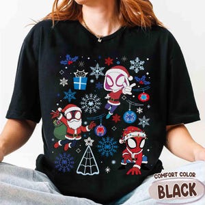 May include: Black Comfort Color t-shirt featuring a Christmas-themed graphic with Spider-Man characters in Santa hats and snowflake designs. The shirt has the words "Comfort Color" and "Black" printed on it.